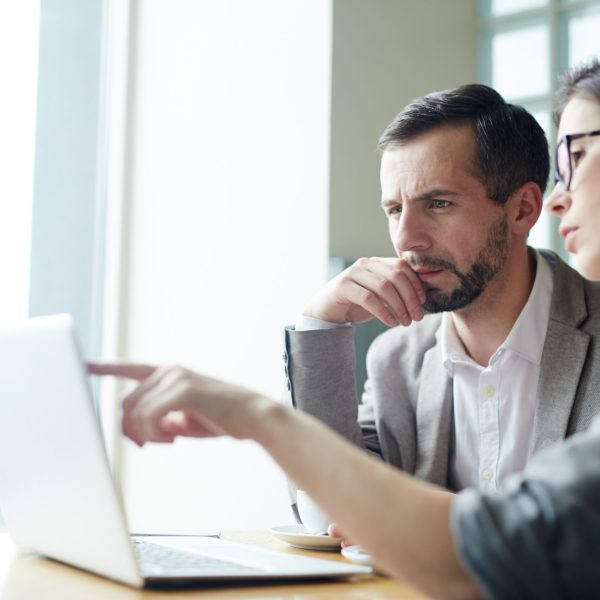 Two analysts discussing online data in front of laptop